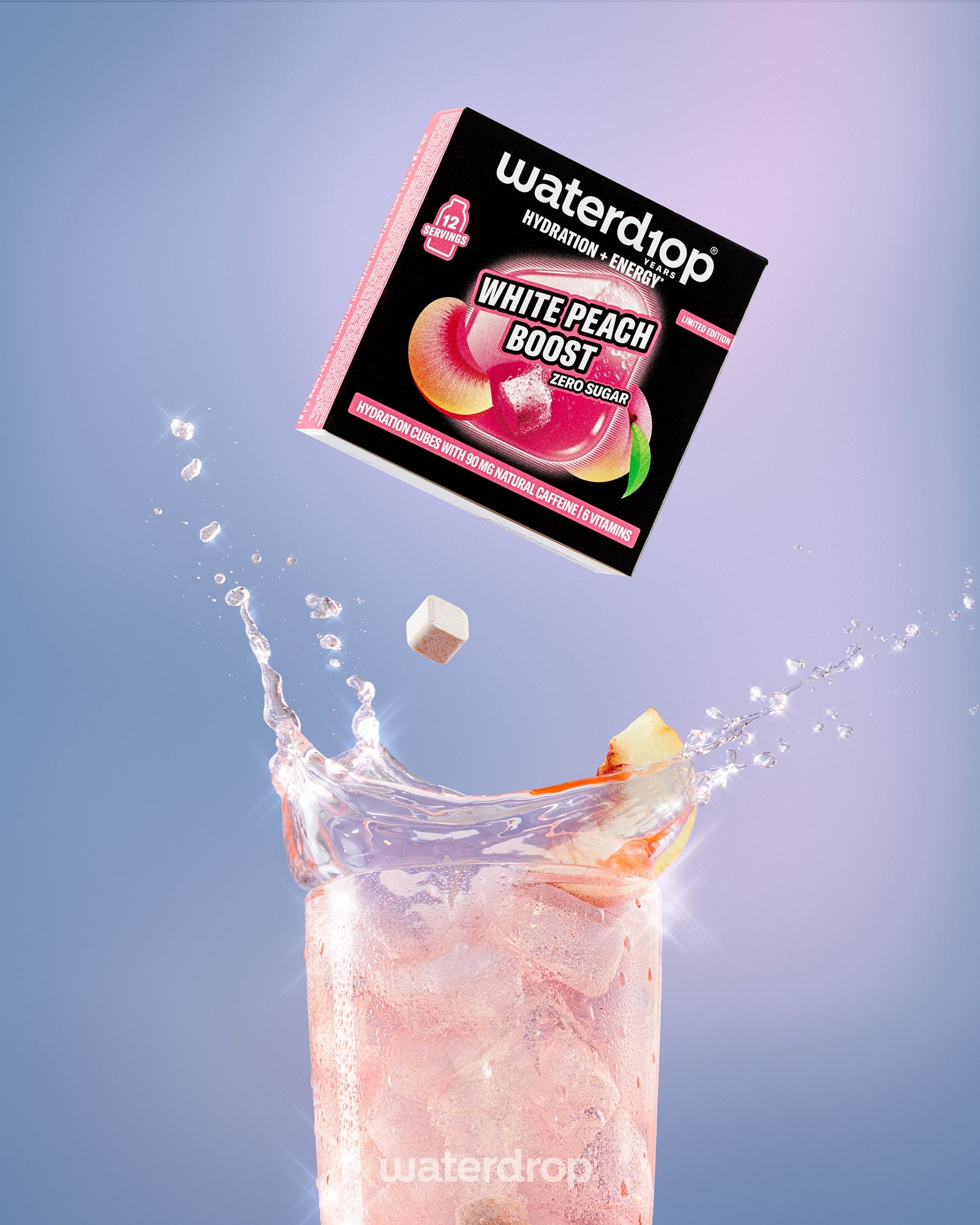 Pudełko napoju White Peach Boost unosi się nad wysokim szklanką z różowym napojem i kostkami lodu.